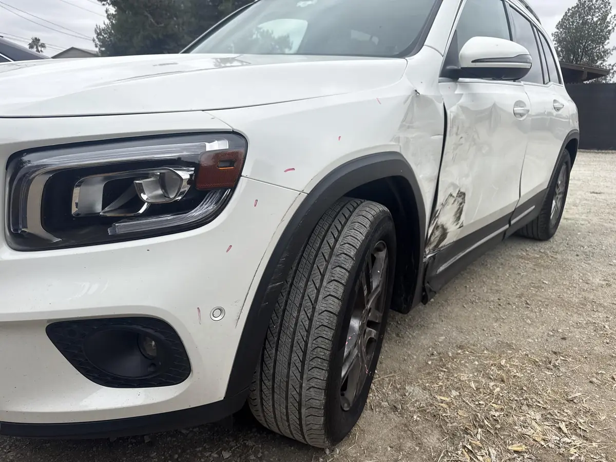 White SUV with damage along the front fender, wheel arch, and door