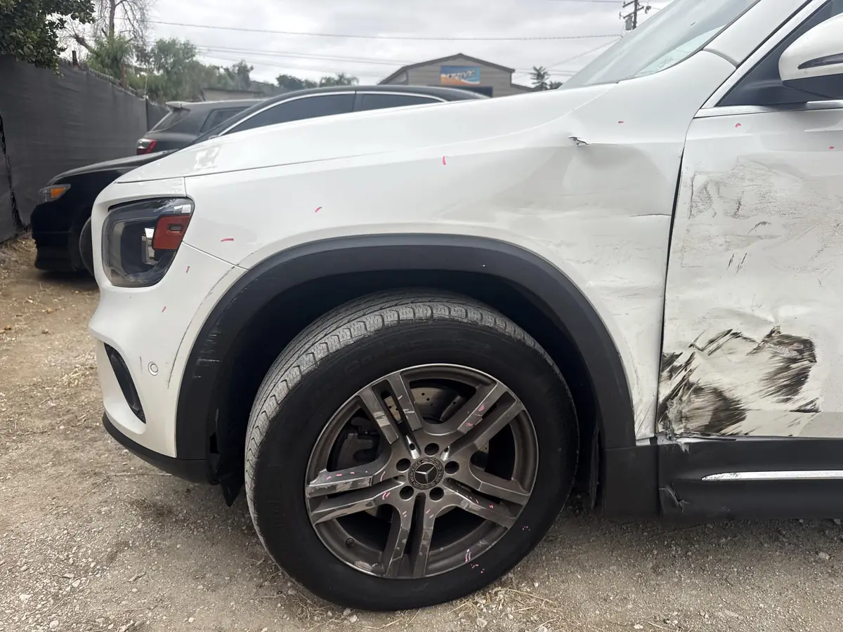 Close-up of a scrape and dent across a white SUV's front fender and door